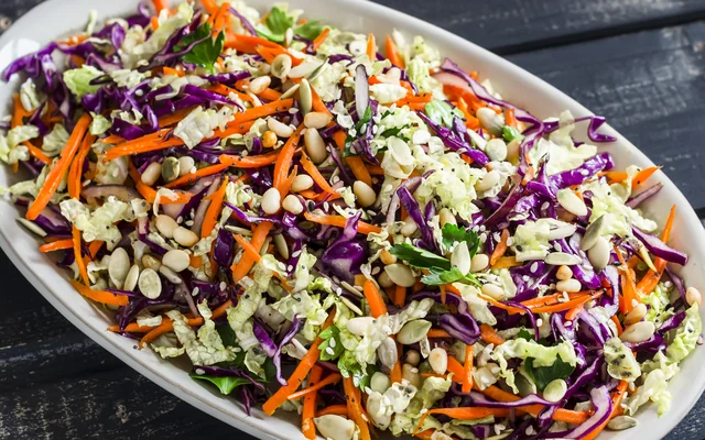 Shredded vegetable slaw with pumpkin seeds on an oval platter