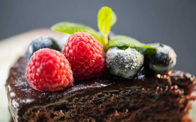 Chocolate cake topped with raspberries, blueberries and mint