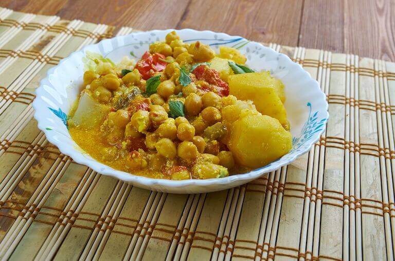 Potato cubes with chickpeas, and other vegetables in a rich yellow sauce.