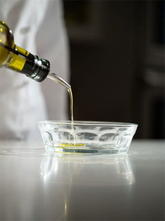 olive oil being poured-into a clear glass dish