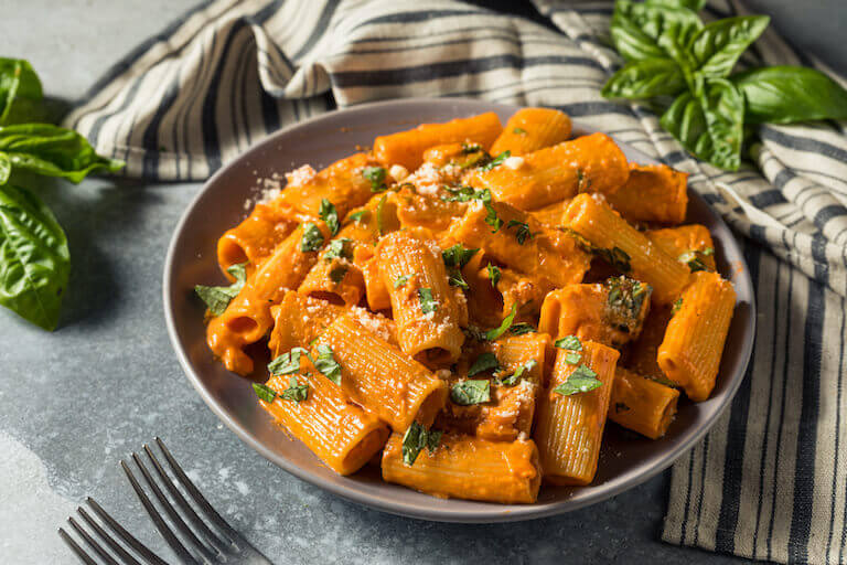 Fresh rigatoni pasta with vodka sauce in a grey bowl on a table