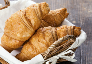 Croissants in basket on wooden table