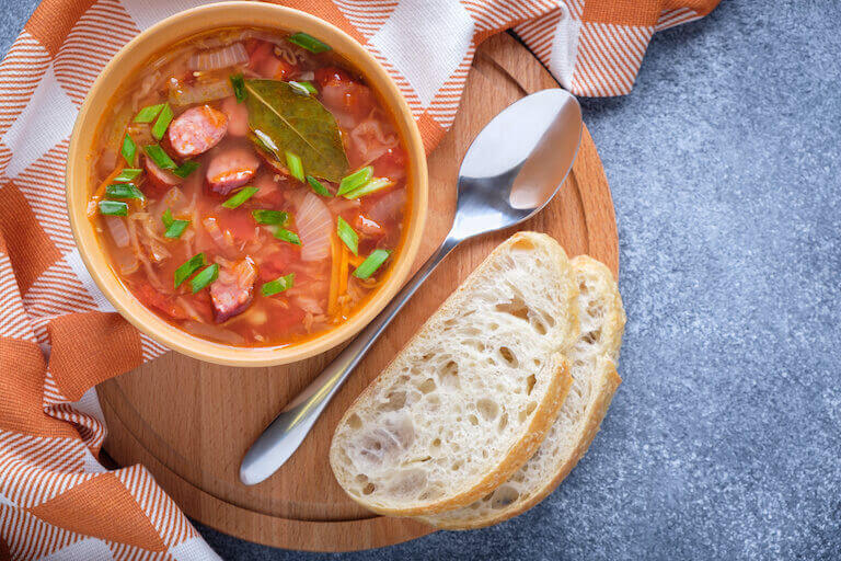 Bowl of tomato soup with sausages and slices of bread