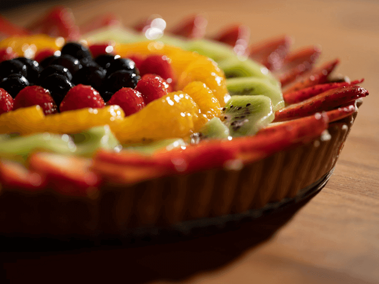 Close up image of a fruit pie with strawberries, kiwis, raspberries, and blueberries