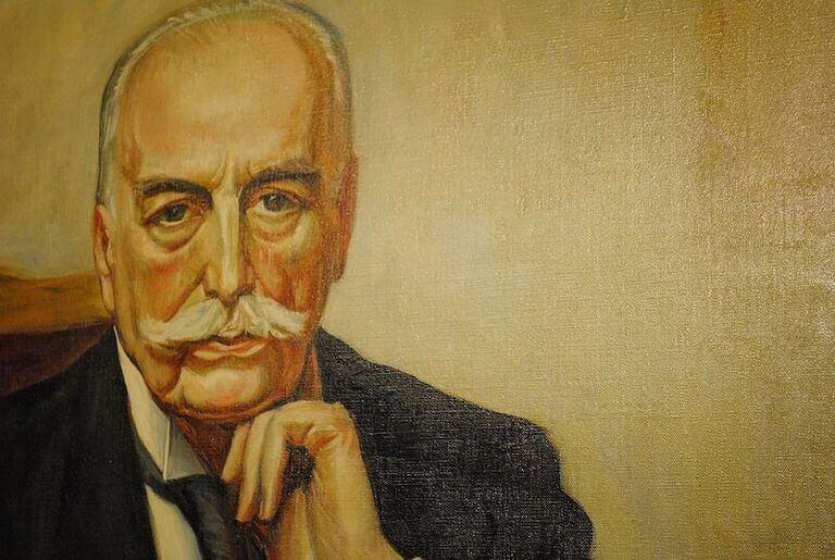 Close up image depicting a realistic painting of Escoffier, dressed in formal attire, with his hand on his chin and looking straight ahead.