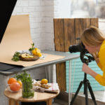 Young woman food photographer taking picture of lemons, mint and ginger in professional studio