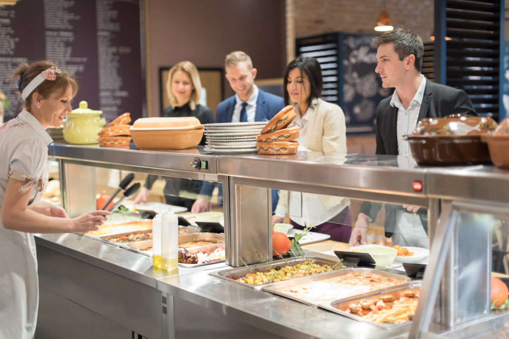 Female line cook serving people in a cafeteria
