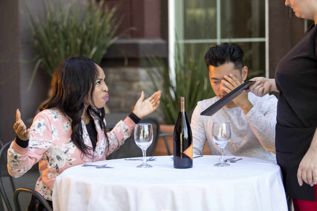 Couple on a date angry and yelling at a waitress in an outdoor restaurant