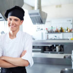 Smiling chef wearing black toque hat in kitchen