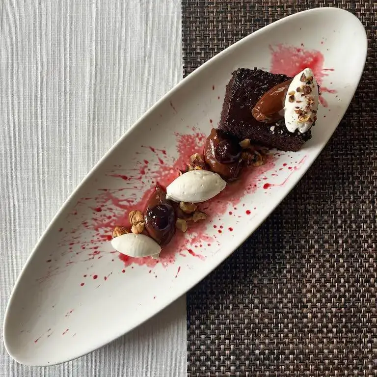 Deconstructed black forest cake plated on a white dish. 
