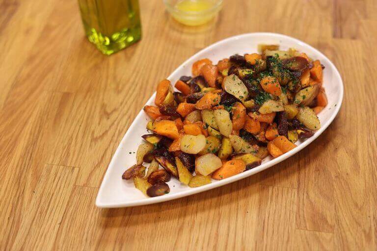Roasted Carrots and other veggies on a white tear drop shaped plate