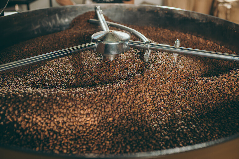 close up view of coffee beans roasting in machine