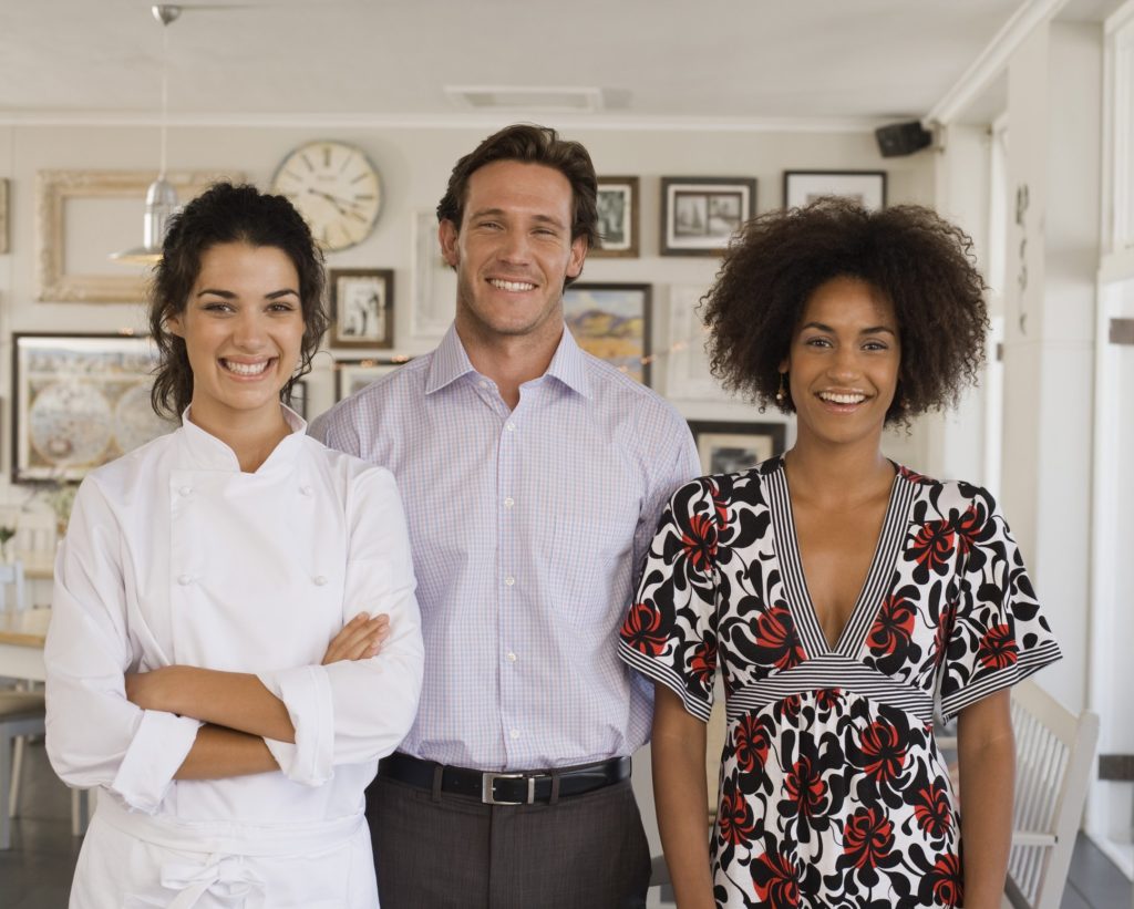 A female chef, a man, and woman in dress standing together