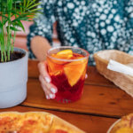 young woman eating pizza and drink negroni