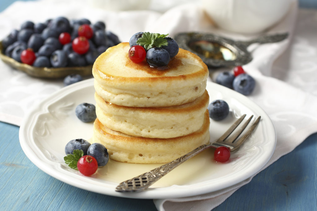 Stack of pancakes with fresh berries and honey