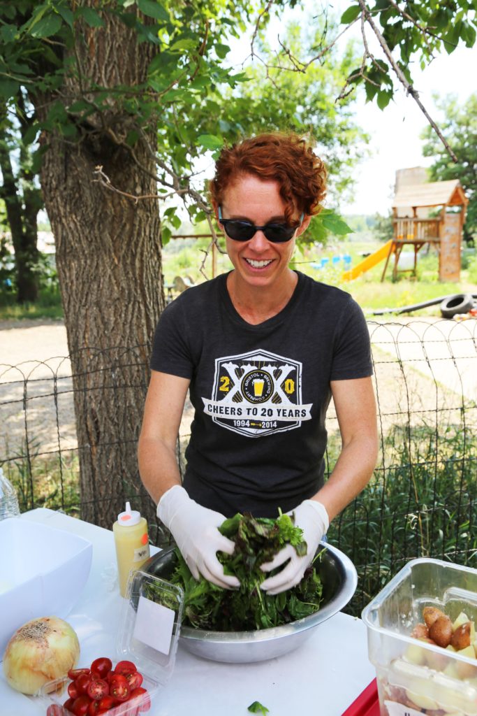 Participant tossing fresh mixed greens to help prepare the meal. 