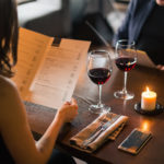 Couple with menu and two wine glasses in a restaurant making order