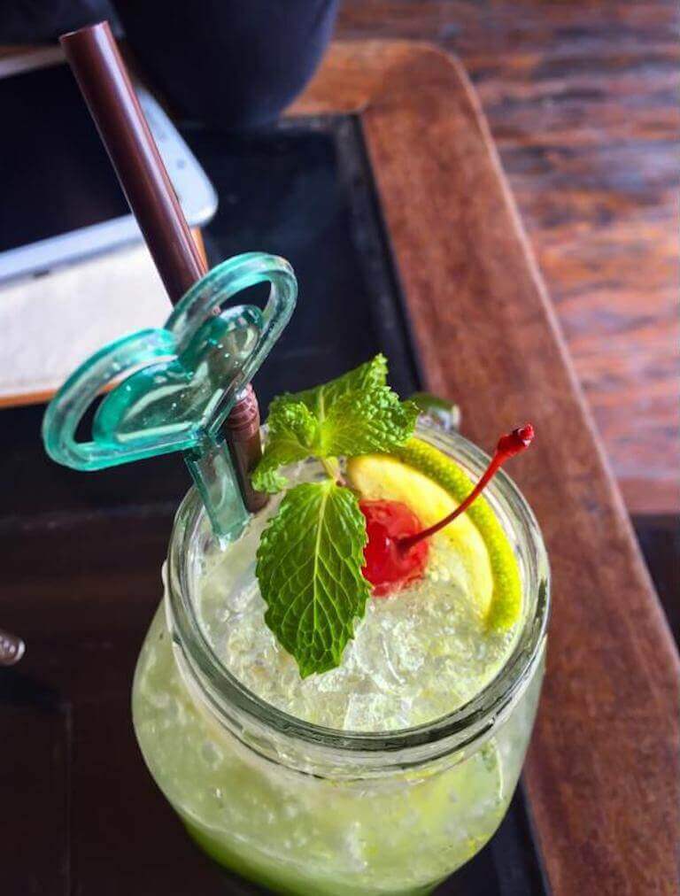 A mocktail with a cherry and mint leaf sits on a table