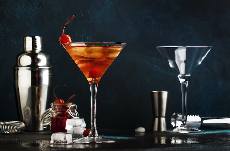 Classic alcoholic cocktail Manhattan with bourbon, red vemuth, bitter, ice and cocktail cherry in glass