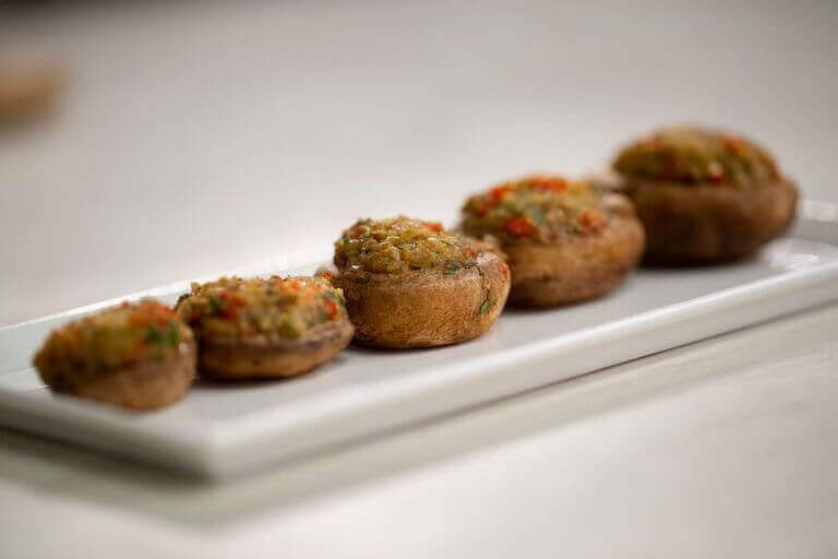 Stuffed mushrooms lined up on a white plate