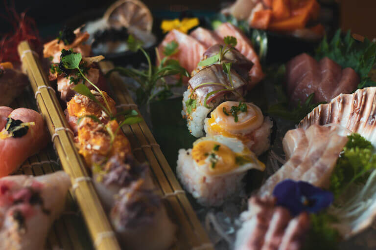 Various types of fusion sushi on a bamboo mat