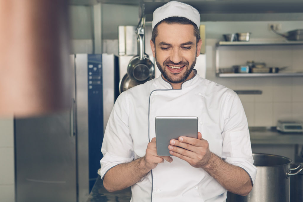 Male chef using a mobile tablet in a commercial kitchen