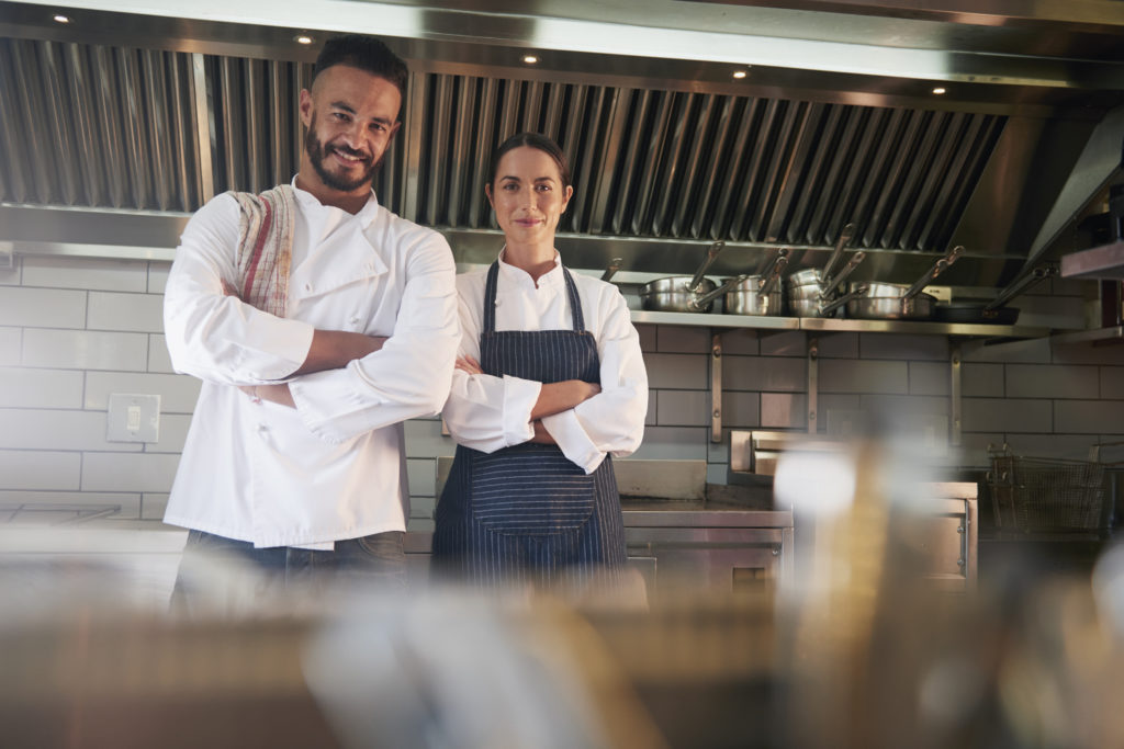 Smiling male and female chef in a commercial kitchen