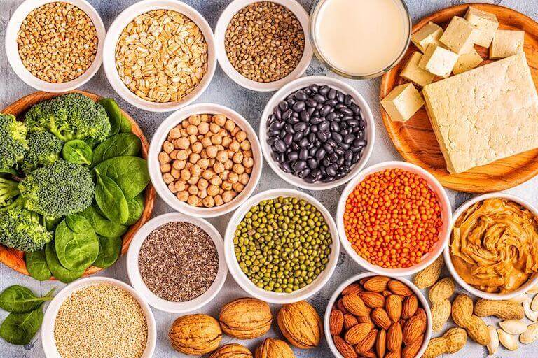 Broccoli, almonds, oats, and other plant based proteins in white bowls on a table