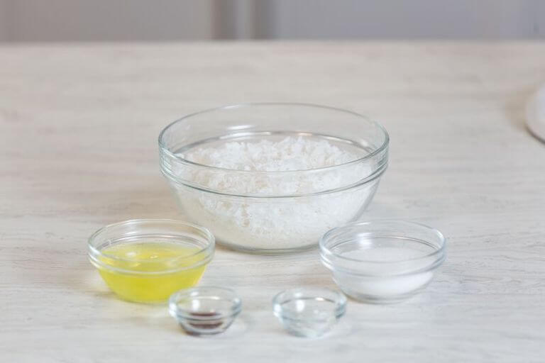 Coconut flakes, oil, sugar and other ingredients in glass bowls