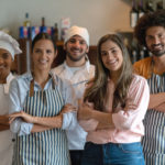 Diverse-smiling-male-and-female-cooks-and-chefs-with-striped-aprons