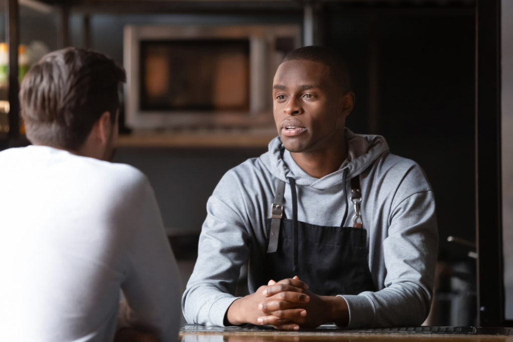 Black male chef talking with caucasian male vacancy candidate in restaurant