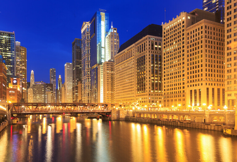 Downtown Chicago at night, with the river in the foreground and the buildings lit up.