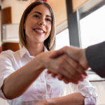 Young woman with white shirt is shaking hands at interview