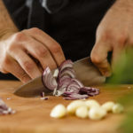 Student cutting an onion in a home cook class