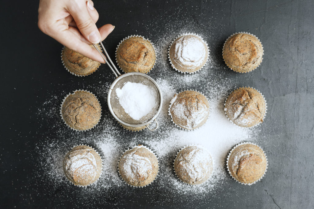 Putting white powdered sugar on muffins aand cupcakes