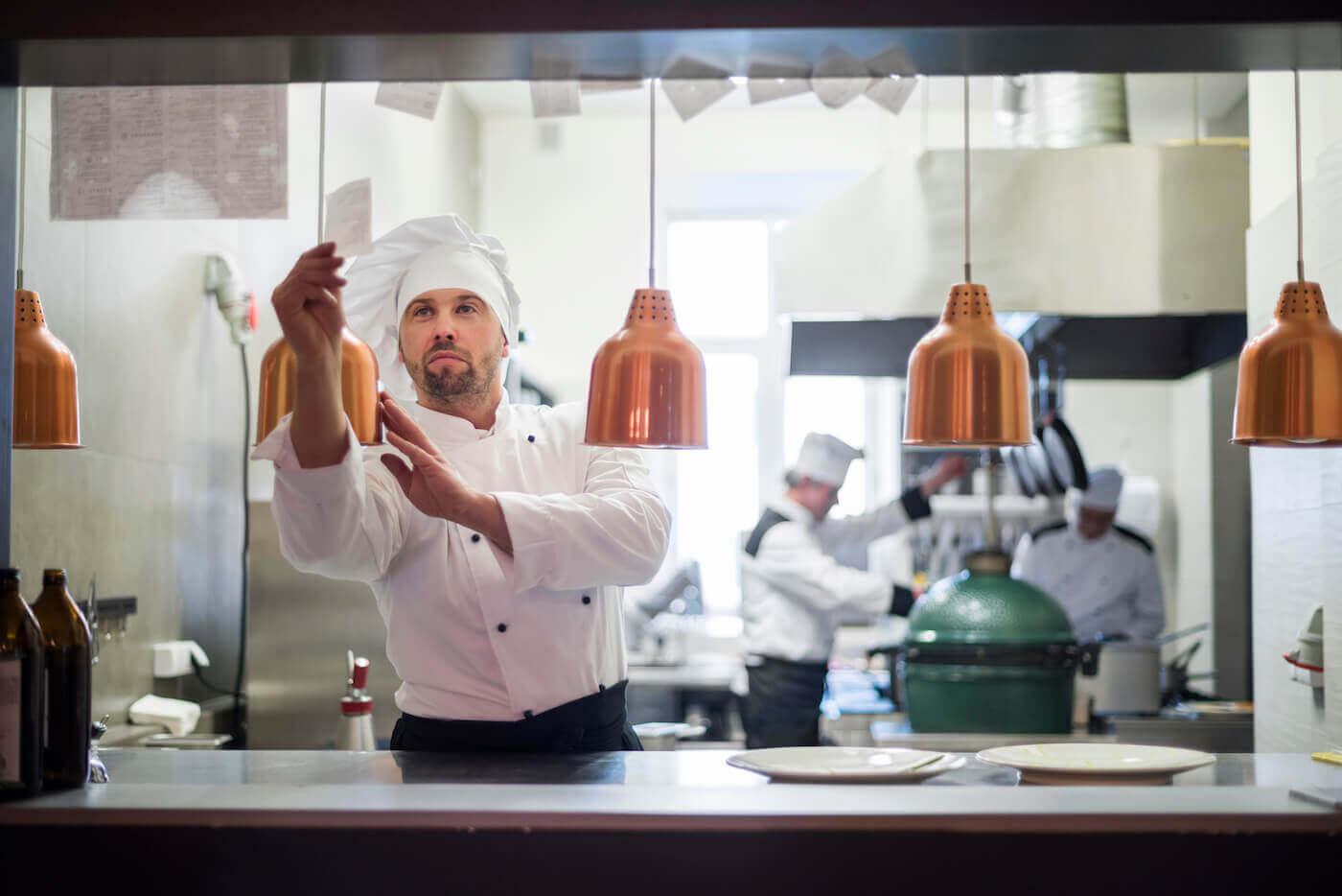 Chef reaching for an order ticket in a commercial kitchen