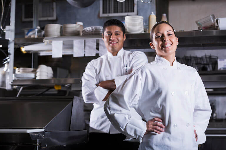 Two Chefs smiling for a photo in a commercial kitchen-768