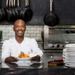 Chef working in a kitchen and showing his plate