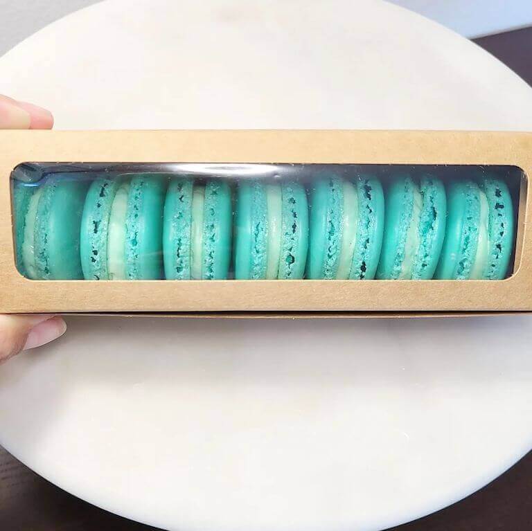 A row of blue vanilla macarons in a box