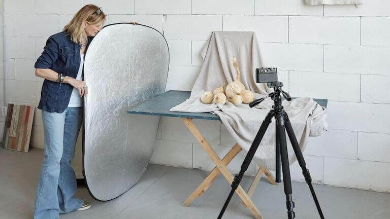 Food stylist holding a reflector while taking photo