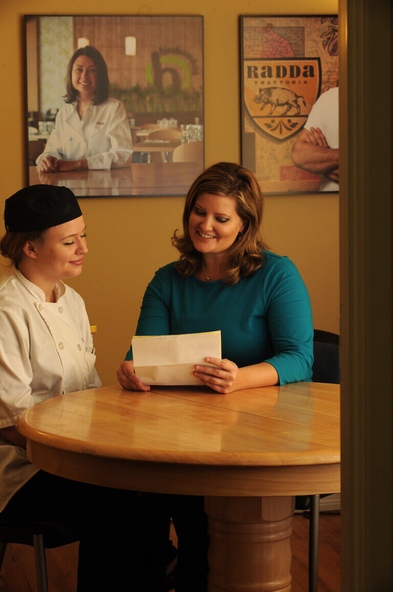 A financial aid advisor is going over paper with female escoffier student in uniform