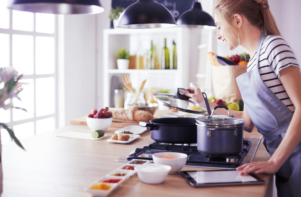 Young woman using a tablet computer to cook in her kitchen