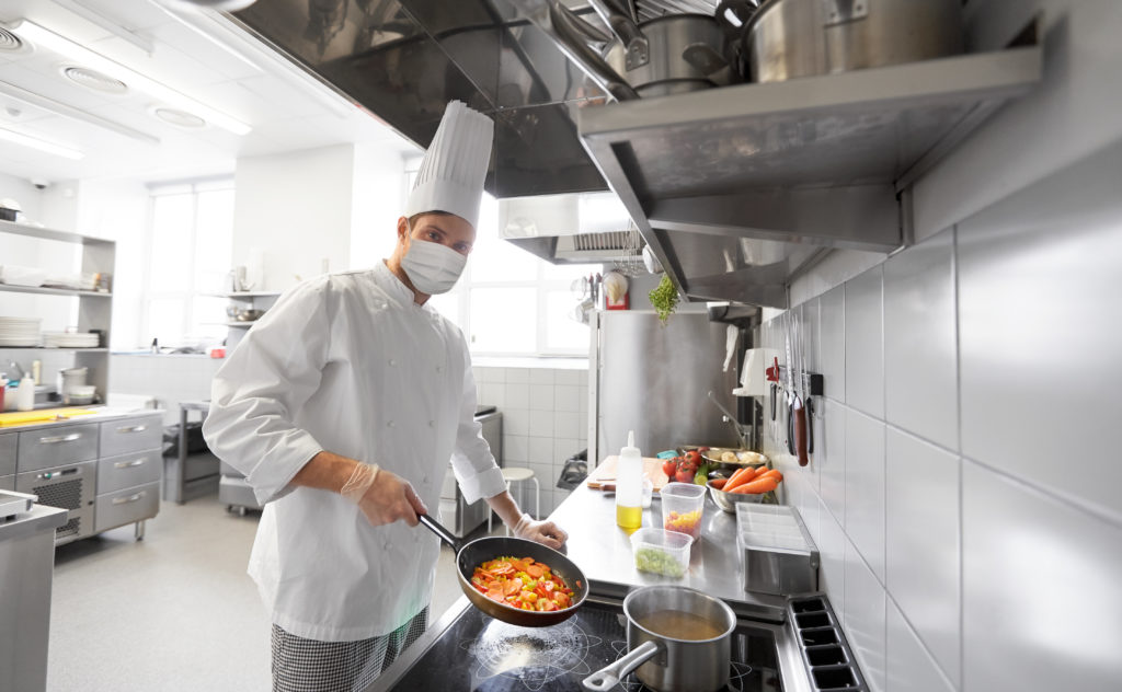 male chef cook wearing medical mask cooking food in frying pan