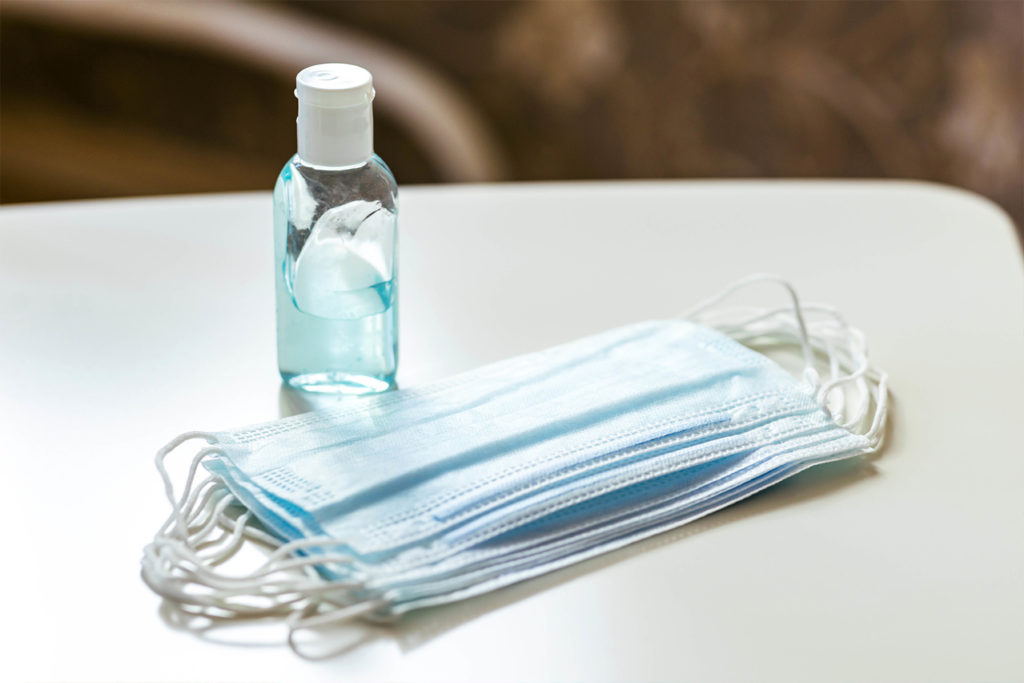 medical masks and hand sanitizer on table