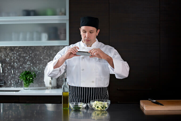 Culinary student taking photo of siced vegetables on phone