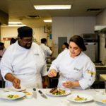 Escoffier culinary students seasoning a plated dish