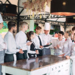 Restaurant manager and his staff in terrace interacting with head chef in restaurant