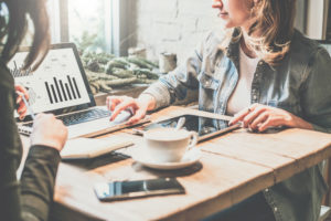 Two young business woman sitting at table in coffee shop