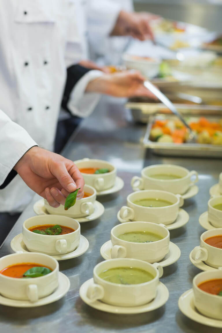Chefs preparing soup in white bowls