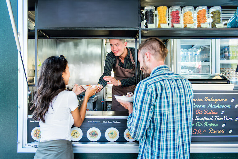 Couple buying pasta from a food truck at an outdoor market